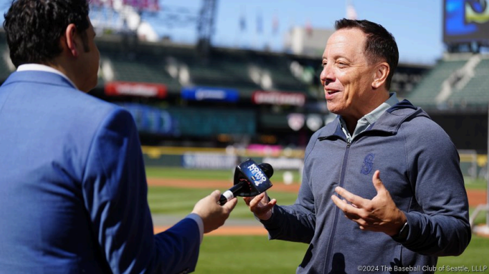 One man being interviewed by another, in a baseball stadium